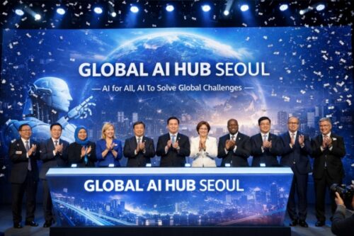 Twelve diverse delegates applaud on stage at the Global AI Hub Seoul event, with a backdrop saying 'GLOBAL AI HUB SEOUL' and a blue cityscape design.