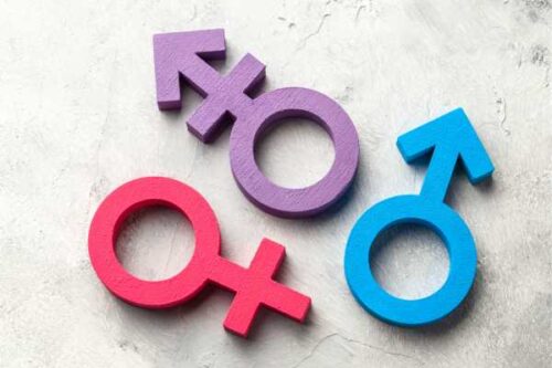 Pink female symbol, blue male symbol, and a purple gender symbol arranged on a light textured background.