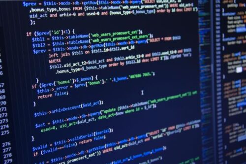 Close-up of a monitor displaying colorful PHP/SQL code with syntax highlighting.”,