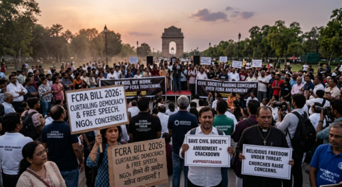 Crowd of protesters at a park holding signs about FCRA Bill 2026 and civil liberties, with a monument in the distance at sunset.